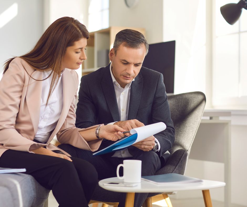 couple sitting on a couch with a pad in front of them, They are looking at the pad