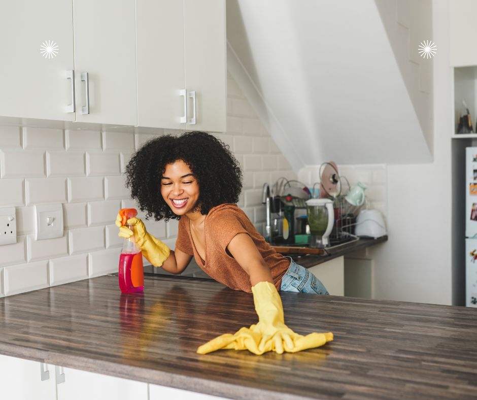 woman cleaning her countertop wearing bright yellow rubber gloves