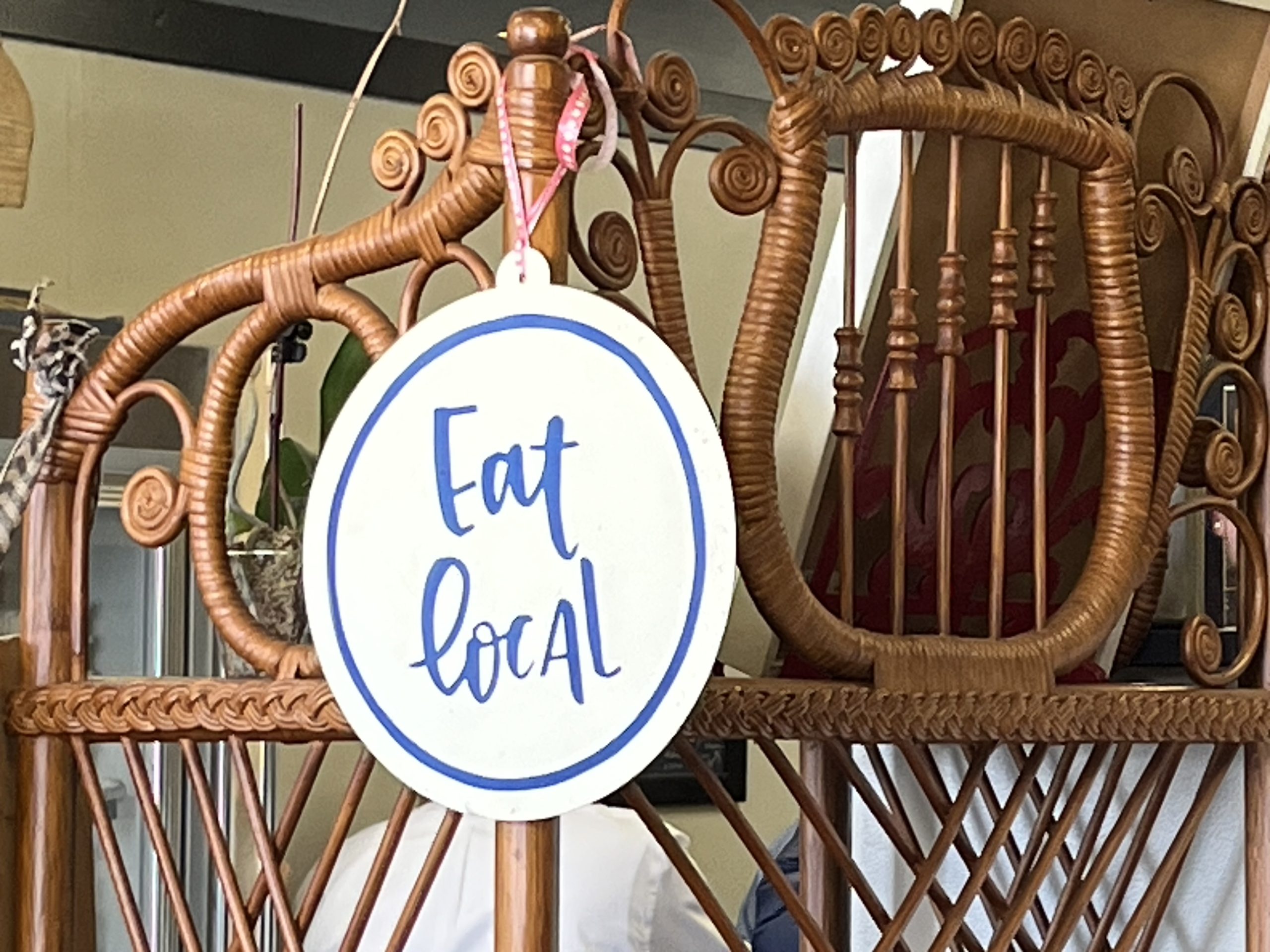 picture of a white sign with blue lettering saying eat local