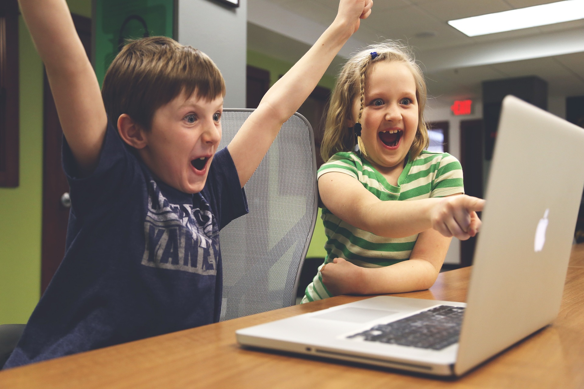 two children cheering in front of a compuer