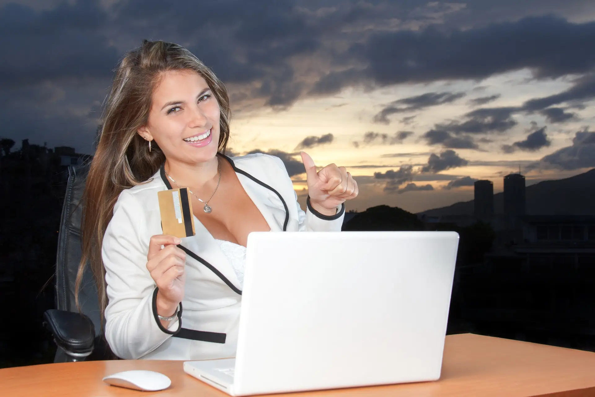 woman holding credit card smiling in front of a computer